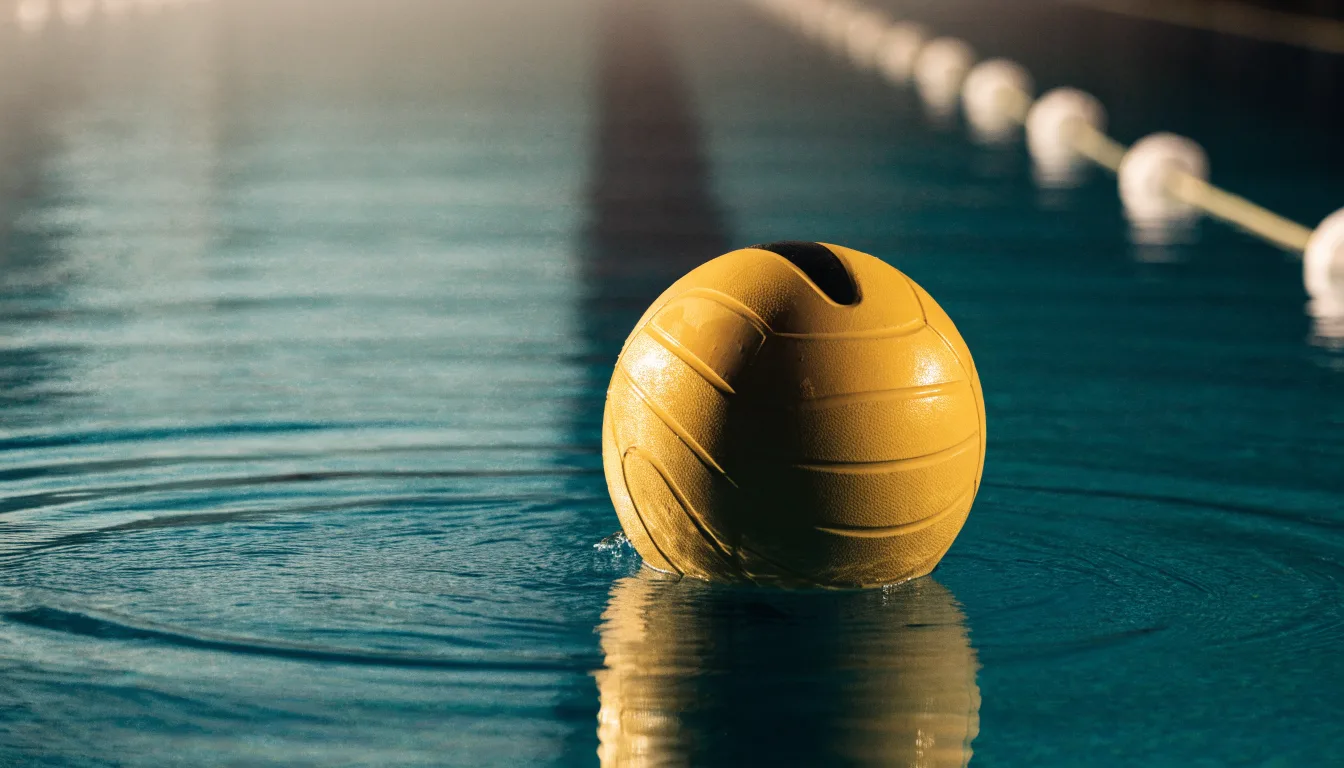 Ein gelber Wasserball treibt in Nahaufnahme auf der Wasseroberfläche neben einer Leine mit Bojen.